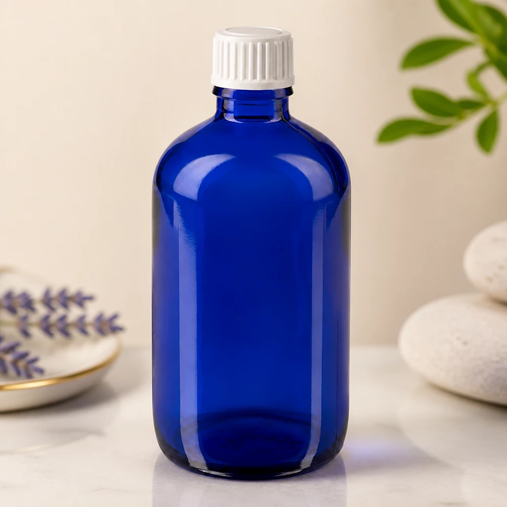 Flacon en verre bleu de 100 ml muni d'un bouchon de sécurité blanc pour enfants, posé sur une surface en marbre à côté de la lavande