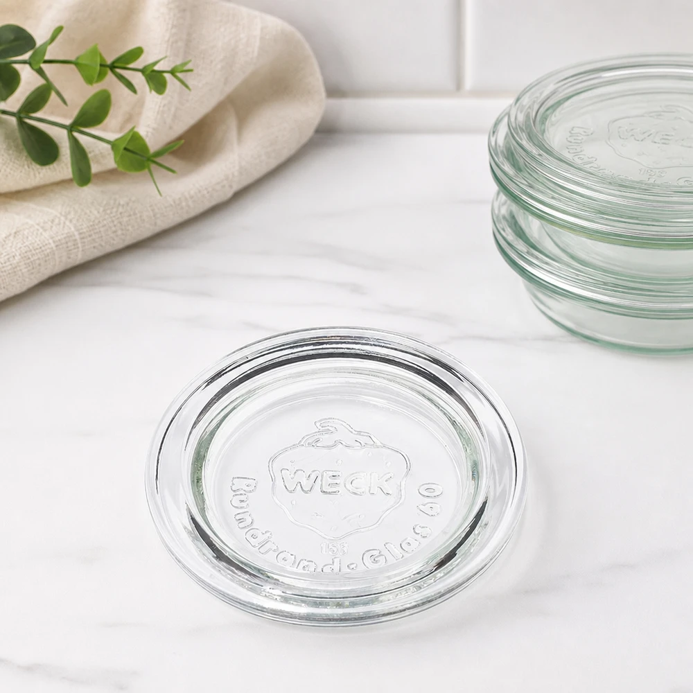 Couvercle de verre RR60 WECK WECK Couvercle en verre RR60 Vue d'empilage de plusieurs couvercles superposés sur marbre avec essuie-tout et branche verte