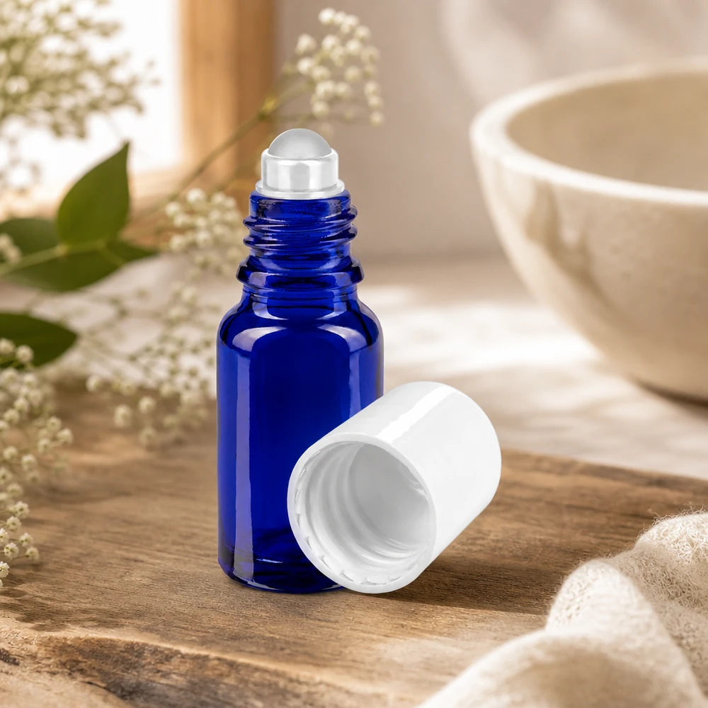 Flacon en verre bleu cobalt de 10 ml à bille, ouvert, dont le bouchon blanc a été retiré, posé sur un support en bois