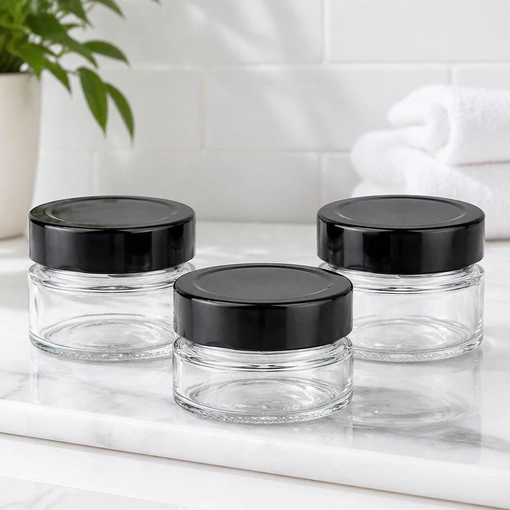 80ml Verre rond avec couvercle BasicSeal noir UNiTWIST Trois pots ronds de 80ml avec couvercles noirs BasicSeal UNiTWIST sur plaque de marbre blanc Salle de bains Ambiente vide