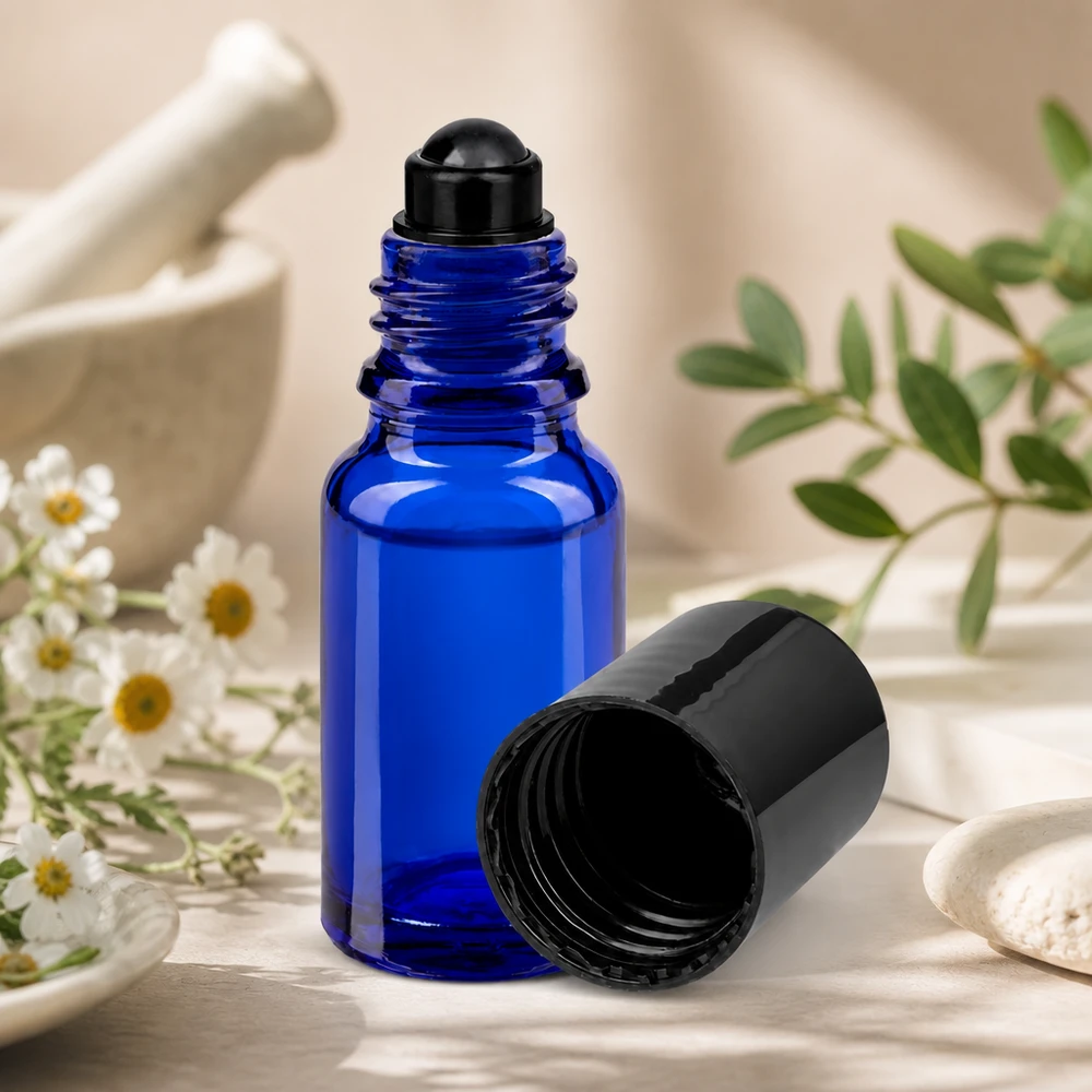 Flacon de déodorant en verre bleu 10 ml, déo à bille vide Flacon roll-on bleu STD de 10 ml avec bouchon noir, à côté d'herbes dans un mortier et de fleurs de camomille