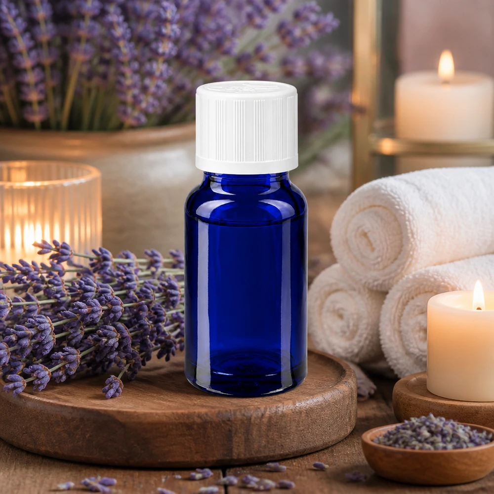 Flacon en verre bleu de 10 ml muni d'un bouchon de sécurité blanc pour enfants, entre des fleurs de lavande et des bougies