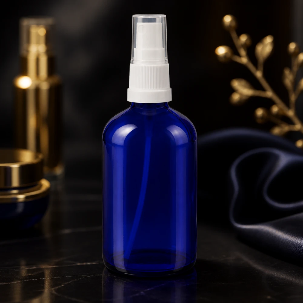 Flacon en verre bleu cobalt de 100 ml, muni d'un vaporisateur blanc et d'un bouchon de protection transparent