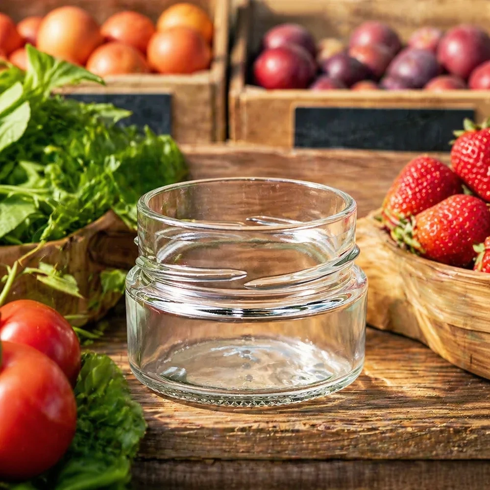 80ml Verre rond sans couvercle (TO58deep) UNiTWIST UNiTWIST Runda80 Verre rond 80ml TO58deep Pot de conserve vide sur table en bois avec fruits et légumes frais en arrière-plan