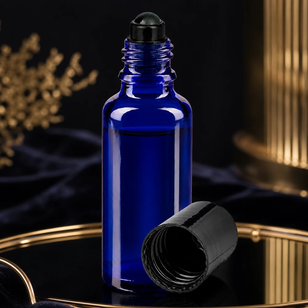 Flacon de déodorant en verre bleu 30 ml, déo à bille vide Flacon roll-on bleu de 30 ml avec un bouchon à vis noir ouvert, posé sur un plateau doré