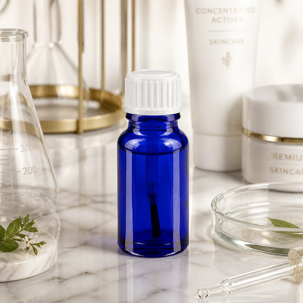 Flacon de pharmacie bleu 10ml bouchon vissable blanc pinceau Petite bouteille en verre bleue de 10 ml avec un bouchon à vis blanc, posée sur du marbre parmi du matériel de laboratoire