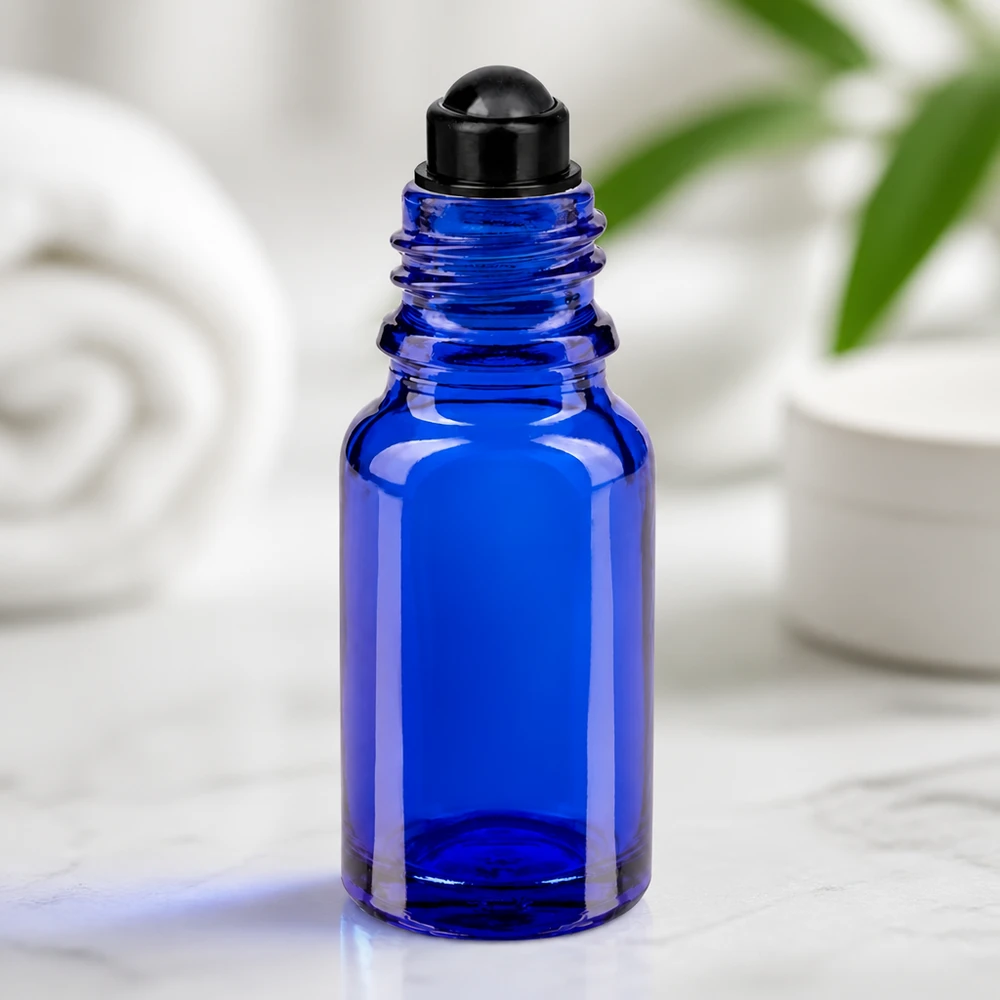 Flacon en verre bleu de 10 ml muni d'un embout roll-on noir, posé sur du marbre devant un fond blanc
