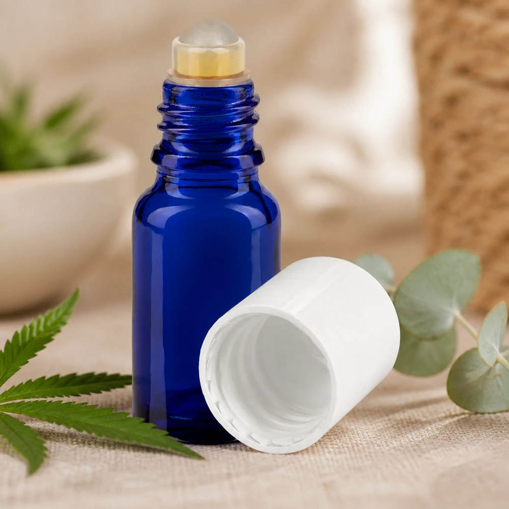 Flacon de pharmacie bleu 10ml Roll-On bouchon blanc Flacon roll-on bleu de 10 ml avec un bouchon blanc, posé à côté de feuilles de chanvre et d'eucalyptus sur un tissu en lin