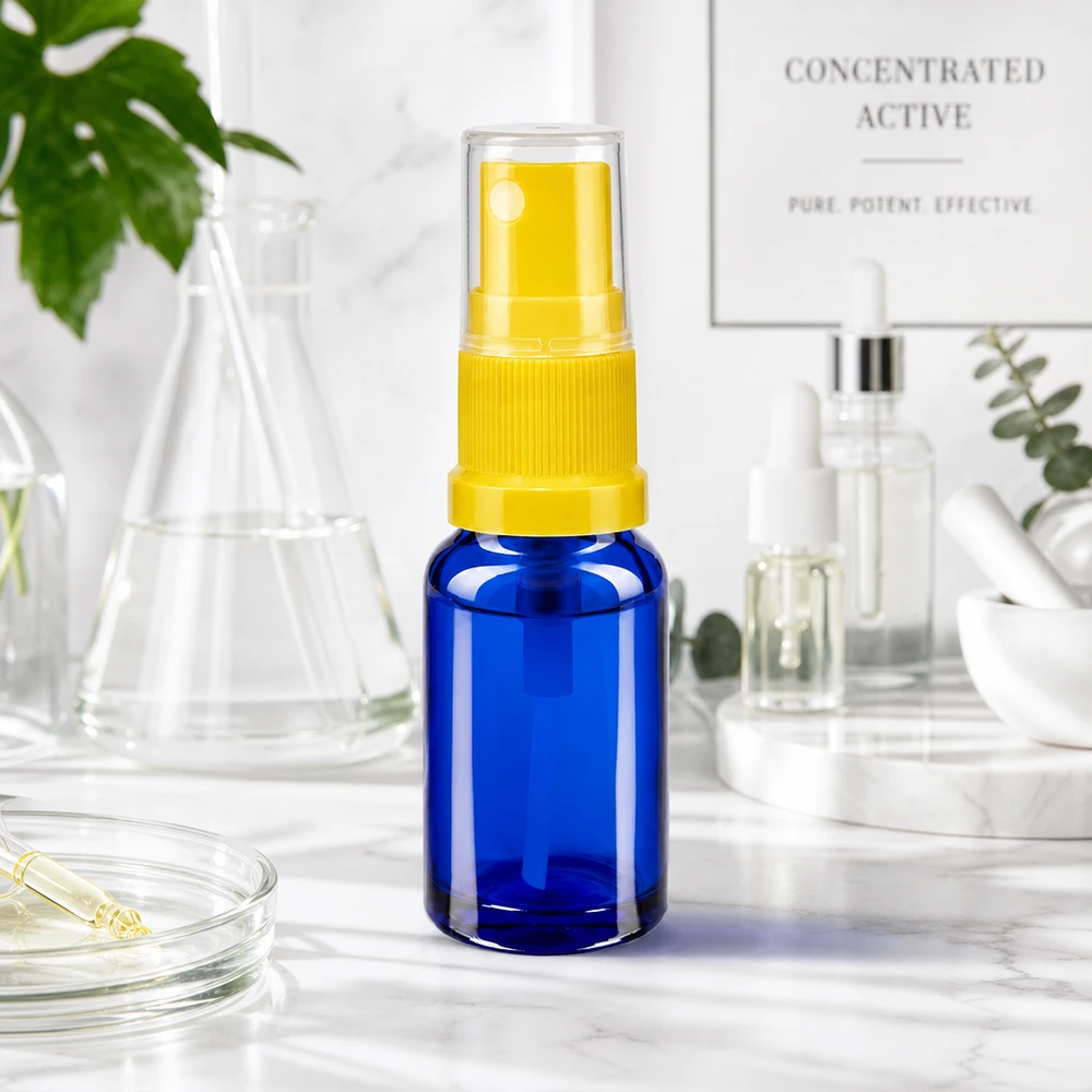 Flacon de pharmacie bleu 10ml embout spray jaune Flacon bleu de 10 ml muni d'un vaporisateur jaune et d'un capuchon de protection, posé sur une surface en marbre blanc