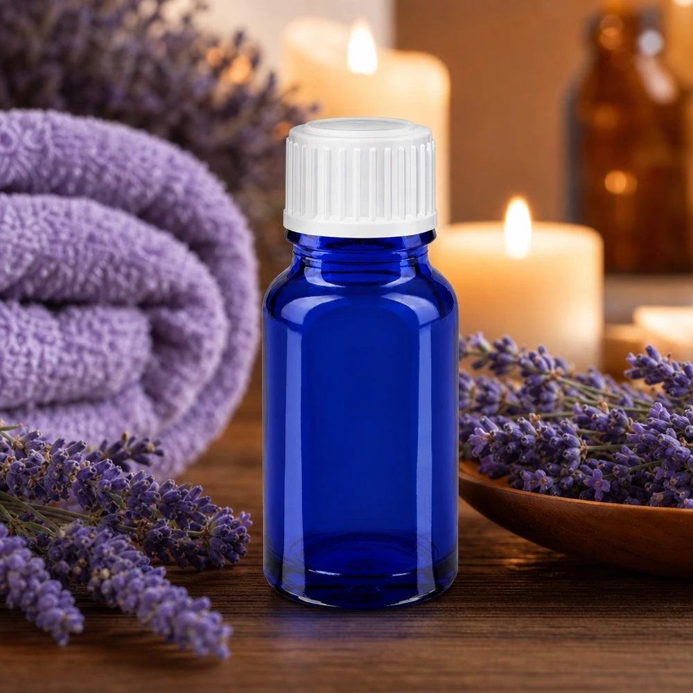 Flacon en verre bleu de 10 ml avec un bouchon blanc, entouré de fleurs de lavande et de bougies