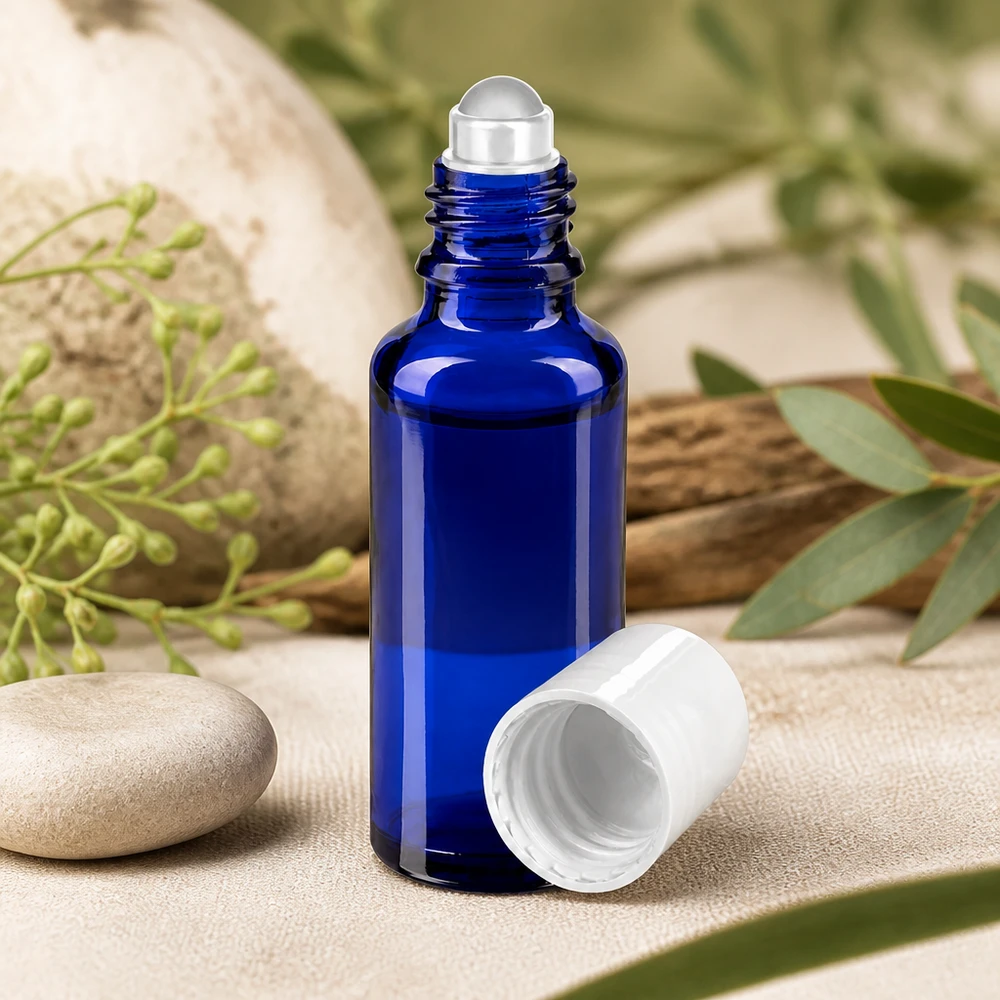 Flacon de pharmacie bleu 30ml Roll-On bouchon blanc Flacon en verre d'apothicaire bleu de 30 ml, muni d'un applicateur à bille en acier inoxydable et d'un bouchon à vis blanc posé sur une pierre naturelle