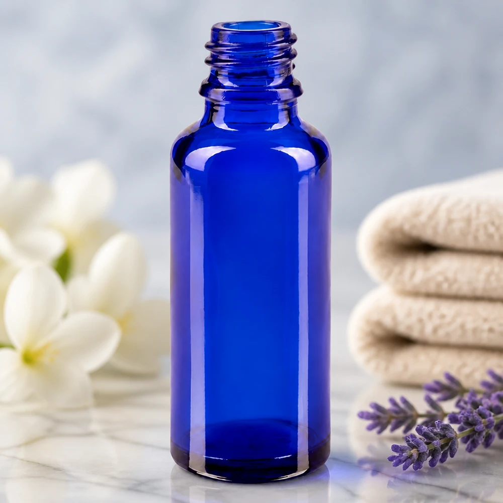 Flacon compte-gouttes pour pharmacie 30 ml DIN18 - verre bleu Flacon de pharmacie ApoGlas vide de 30 ml, bleu royal, à côté d'une branche de lavande et de fleurs blanches