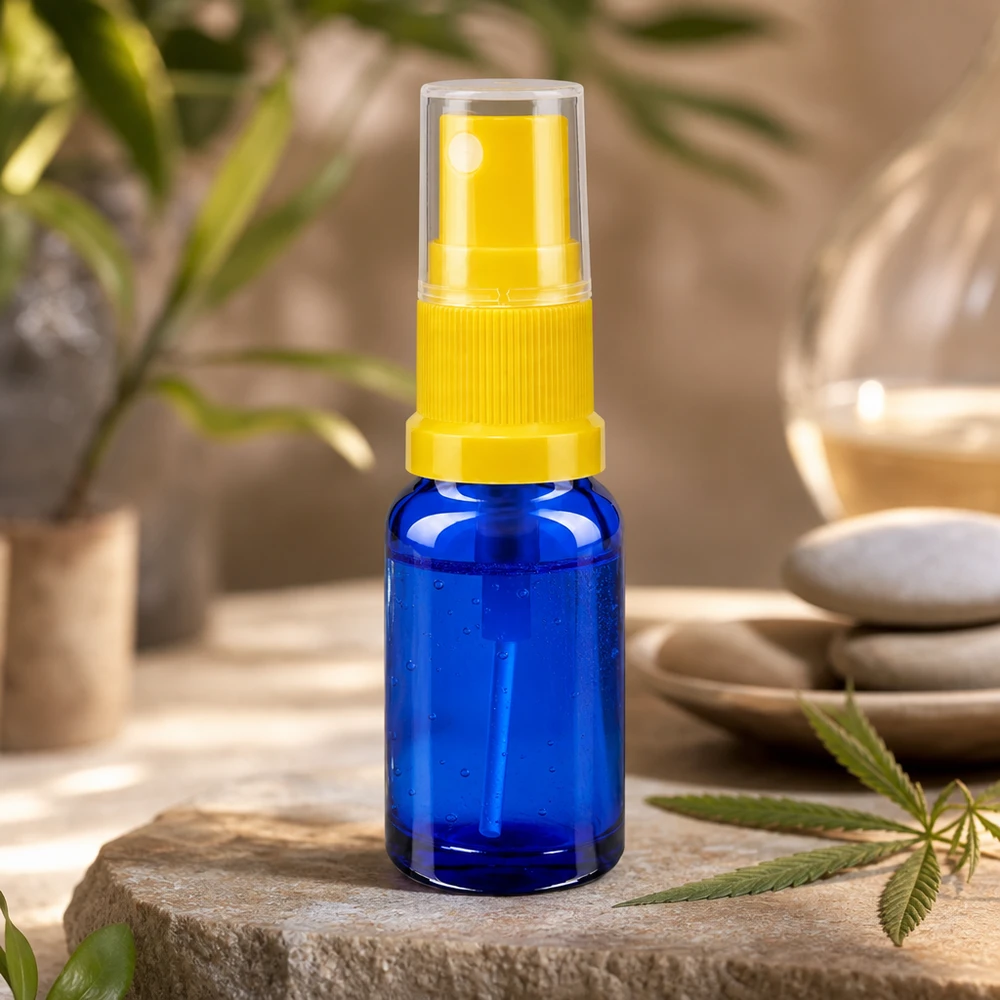 Flacon de pharmacie bleu 10ml embout spray jaune Mini-flacon compte-gouttes bleu de 10 ml avec vaporisateur jaune transparent, posé sur une pierre naturelle ornée d'une feuille de cannabis