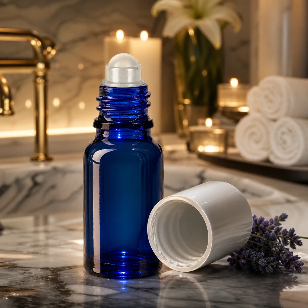 Flacon de pharmacie bleu 10ml Roll-On bouchon blanc Flacon roll-on bleu cobalt de 10 ml avec applicateur à bille, posé sur du marbre à côté de fleurs de lavande