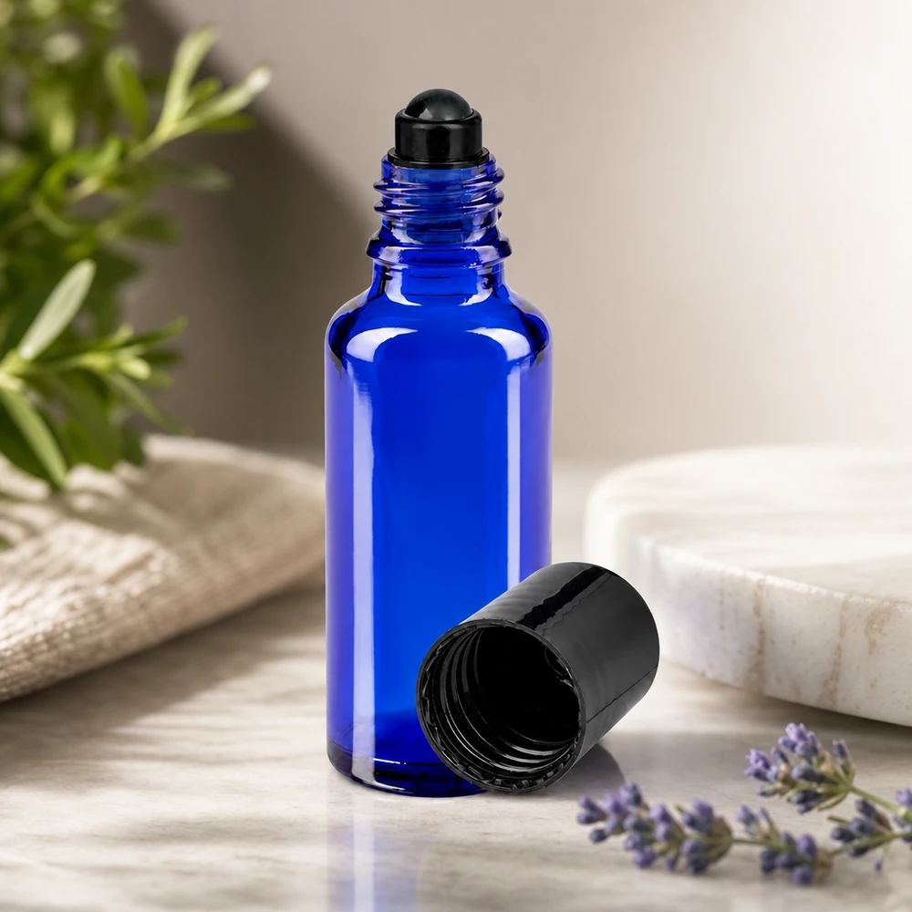 Flacon de déodorant en verre bleu 30 ml, déo à bille vide Flacon en verre bleu cobalt de 30 ml à bille, avec un bouchon noir, à côté d'un brin de lavande et d'un brin de romarin