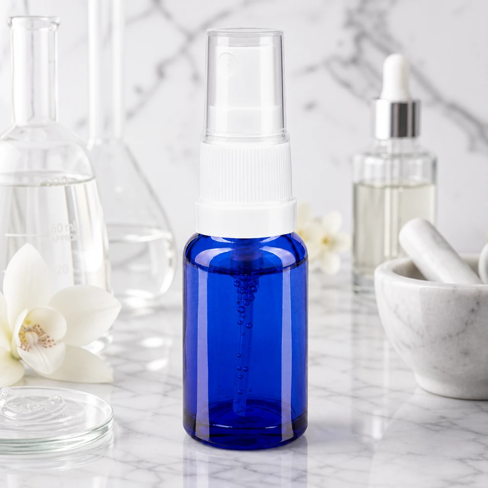 Flacon de pharmacie bleu 10ml embout spray blanc Flacon vaporisateur de 10 ml en verre d'apothicaire bleu, muni d'un vaporisateur blanc, sur un socle en marbre, dans un style de laboratoire