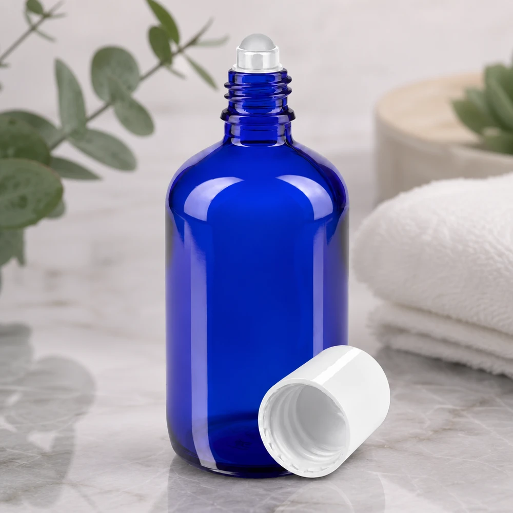 Flacon roll-on de 100 ml ouvert, de couleur bleu cobalt, avec une bille en verre transparente et un bouchon en plastique blanc
