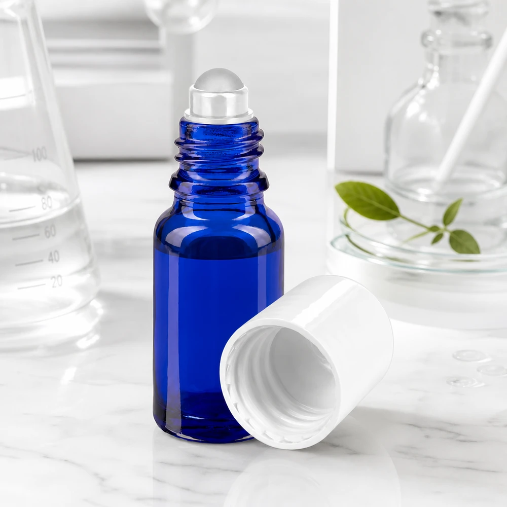 Flacon roll-on bleu cobalt de 10 ml avec une bille en verre transparente et un bouchon blanc sur fond marbré