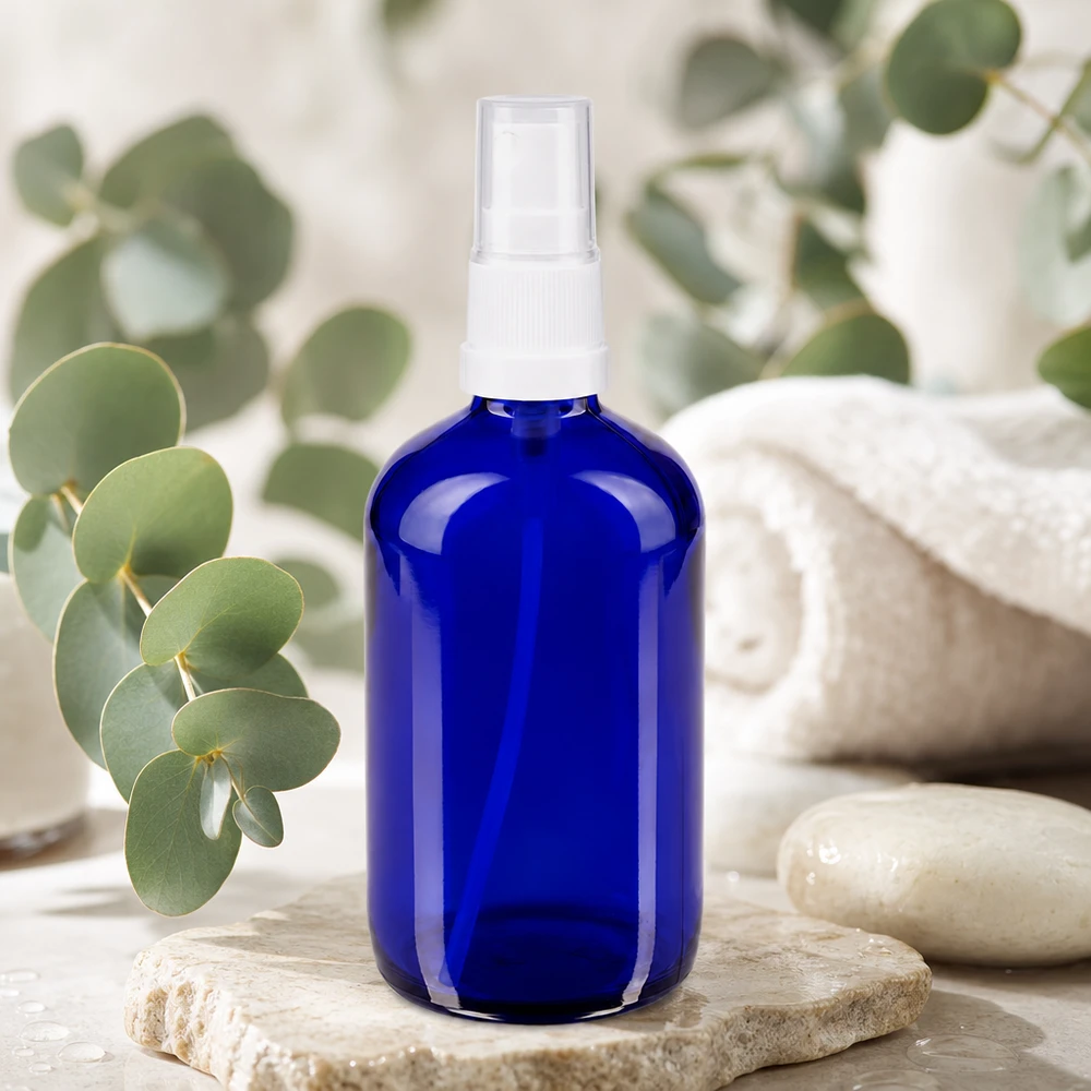 Flacon de pharmacie bleu 100ml embout spray blanc Flacon vaporisateur rond de 100 ml en verre bleu anti-UV, muni d'une pompe vaporisatrice blanche, sur socle en pierre naturelle