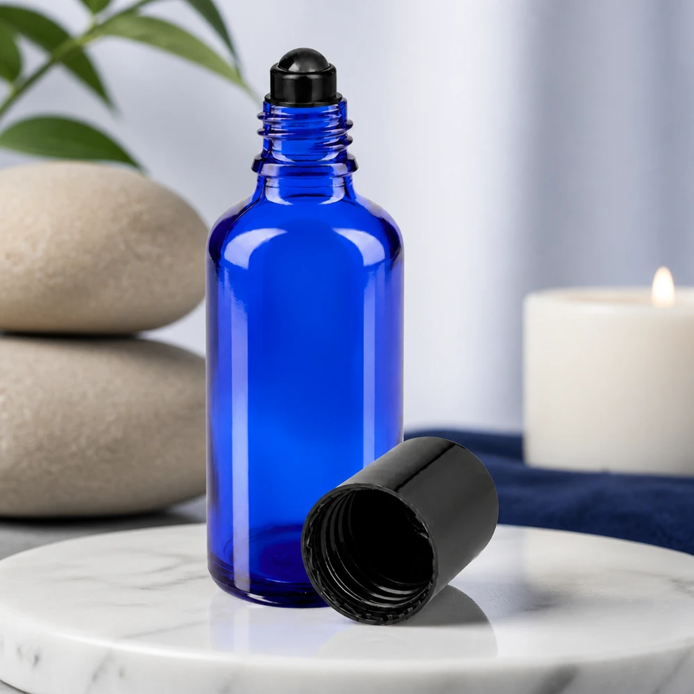Flacon en verre bleu de 50 ml avec un applicateur à bille noir et le bouchon retiré, posé sur du marbre