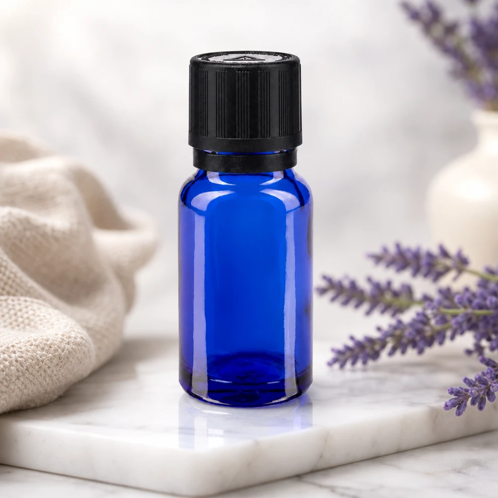 Flacon de pharmacie bleu 10ml bouchon inviolable blanc 1mm,séc. enf. bouchon inviolabilité Flacon compte-gouttes bleu de 10 ml muni d'un bouchon KiSi noir, posé à côté de fleurs de lavande violettes sur un plateau en marbre