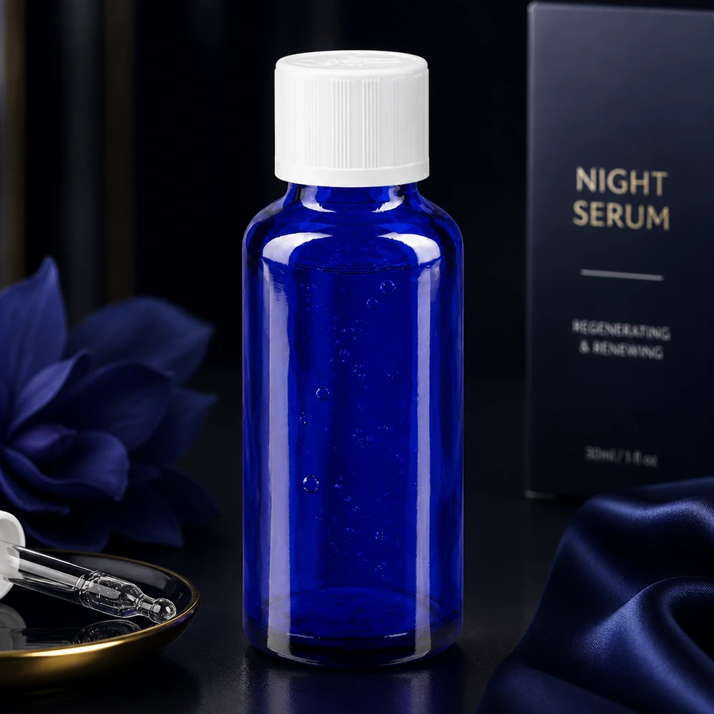 Élégant flacon en verre cobalt de 30 ml destiné à un sérum de nuit, muni d'un bouchon KiSi blanc sur fond foncé