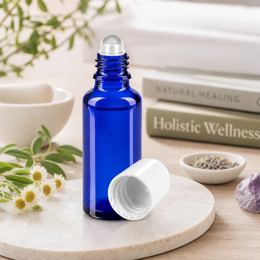 Flacon roll-on cylindrique de 30 ml, bleu cobalt avec un bouchon blanc, à côté de plantes médicinales et d'une améthyste