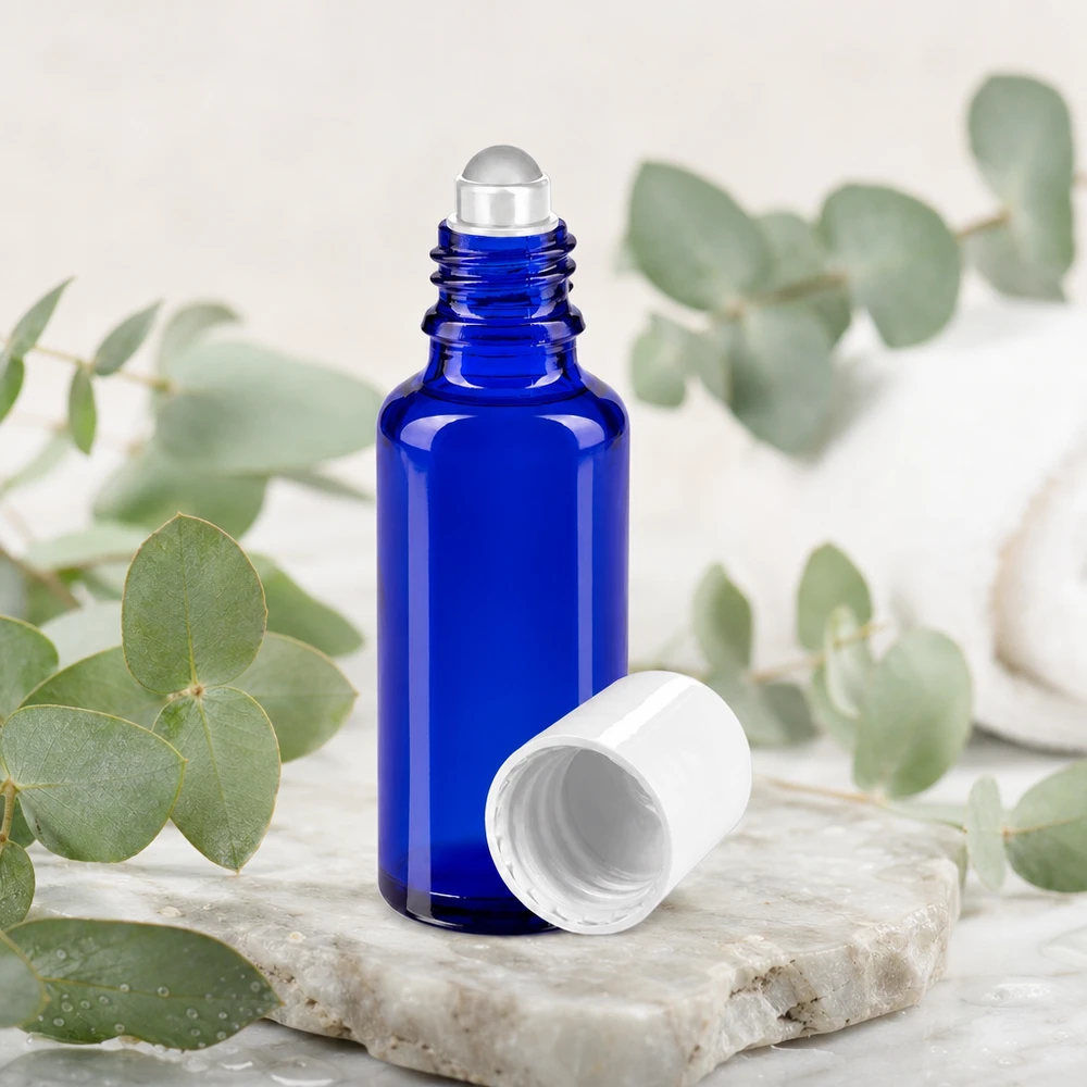 Flacon roll-on de 30 ml en verre d'apothicaire bleu cobalt, muni d'un bouchon blanc et orné de brindilles d'eucalyptus