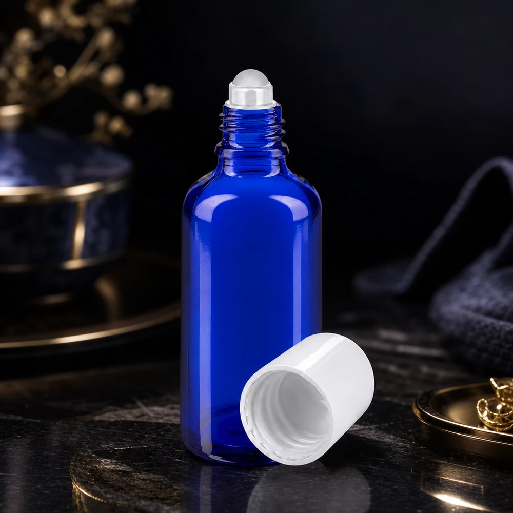 Flacon en verre de pharmacie bleu de 50 ml ouvert, muni d'un bouchon à bille blanc, posé sur une surface en marbre foncé