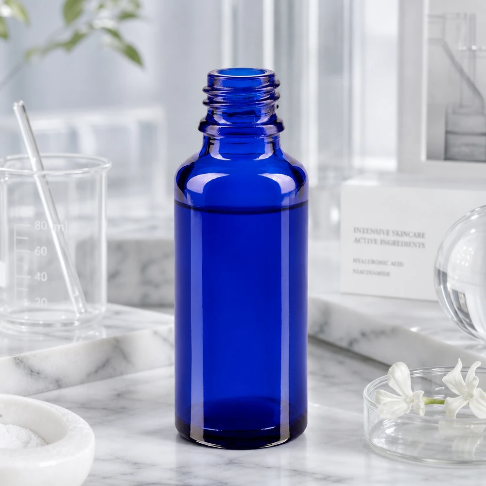 Flacon compte-gouttes pour pharmacie 30 ml DIN18 - verre bleu Flacon ApoGlas bleu cobalt de 30 ml, dans un décor de laboratoire, avec un gobelet doseur et des ingrédients de soins de la peau