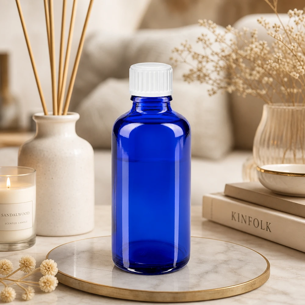 Flacon de pharmacie de 50 ml, bleu cobalt, muni d'un bouchon standard blanc, posé sur un plateau en marbre