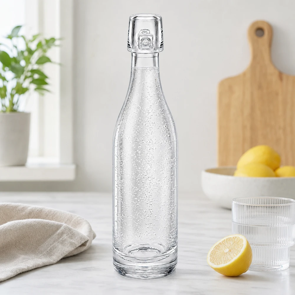 Bouteille en verre de 50 ml UNiTWIST remplie d'eau gazeuse dans une cuisine moderne à côté de citrons et de verres Plan de travail blanc