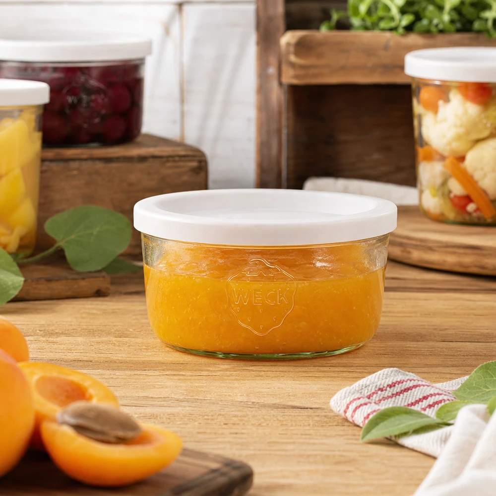 165ml bocal conique avec couvercle fraîcheur WECK RR80 WECK Pot renversé de 165ml rempli de confiture orange dans un environnement de cuisine naturel avec des bocaux en arrière-plan