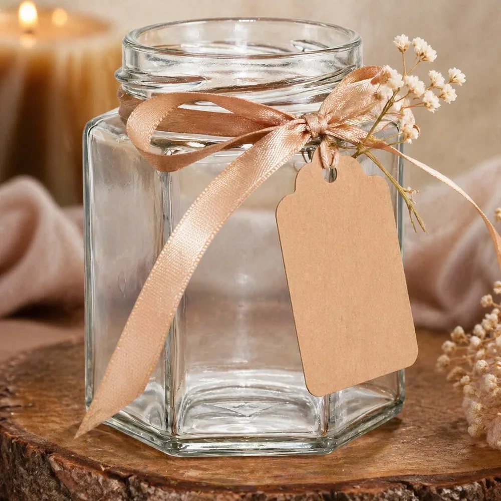 Pot de conserve vide hexagonal 196ml avec bouchon à vis, décoré avec un ruban beige et un pendentif sur un fond en bois
