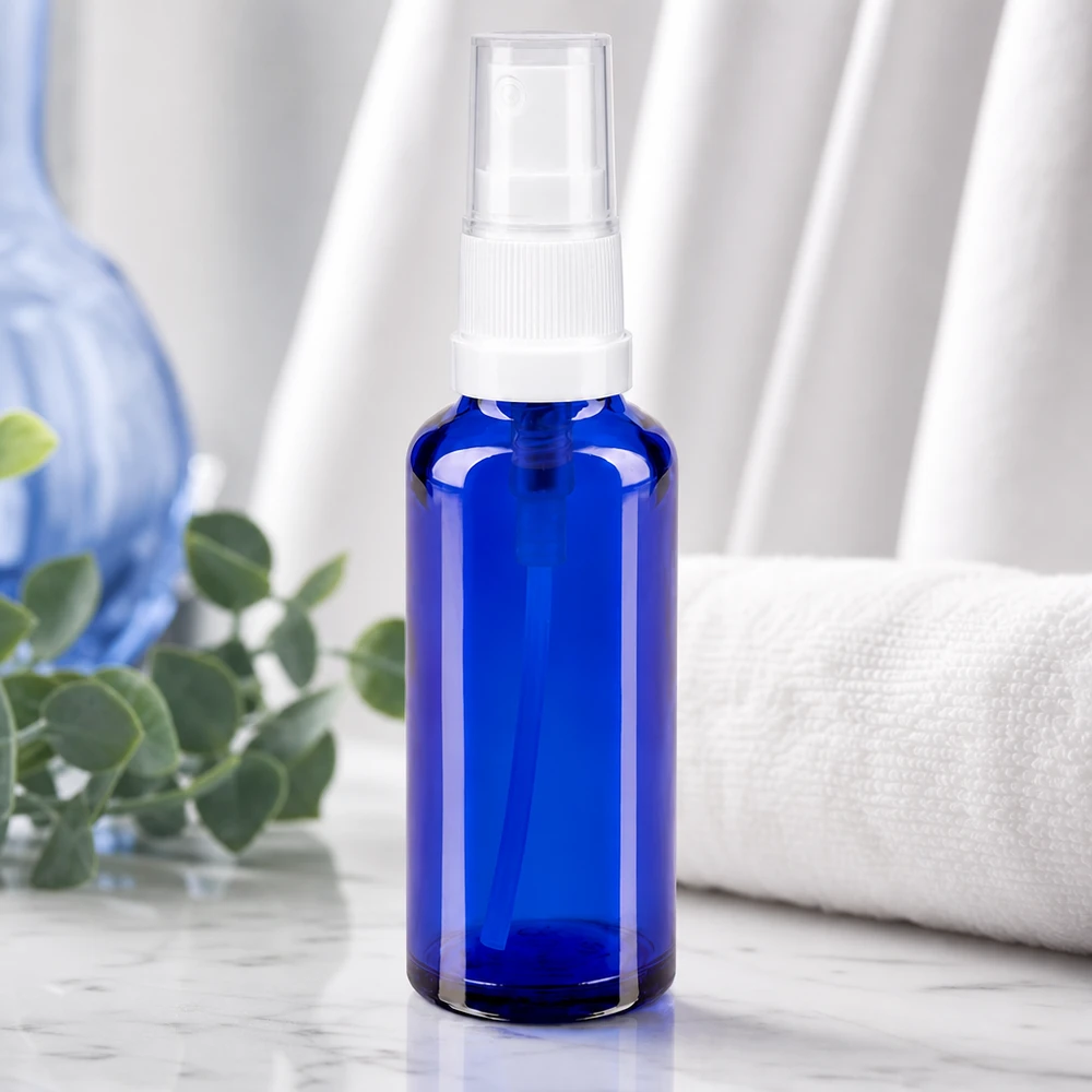 Flacon vaporisateur bleu cobalt en verre d'apothicaire, muni d'un bouchon transparent, posé sur du marbre