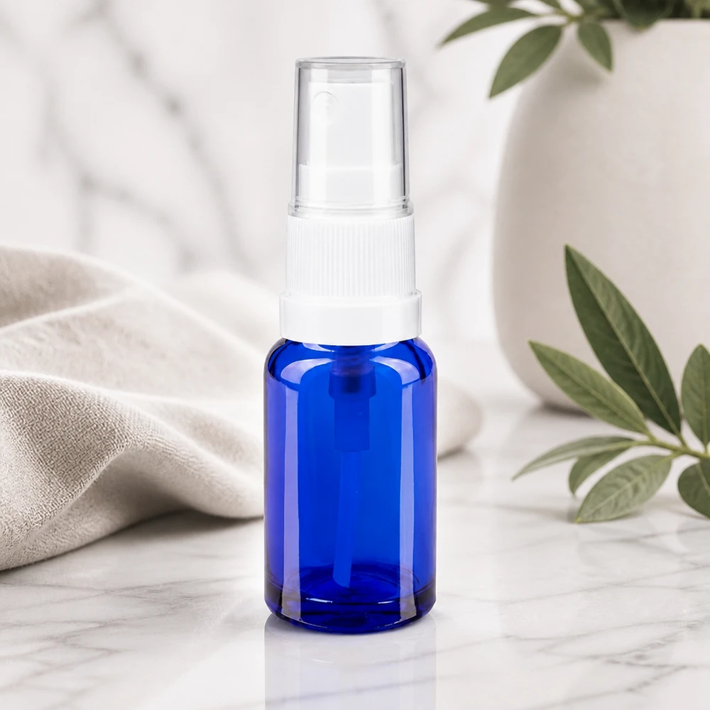 Flacon en verre de pharmacie bleu de 10 ml, muni d'un vaporisateur standard blanc et d'un bouchon de protection transparent