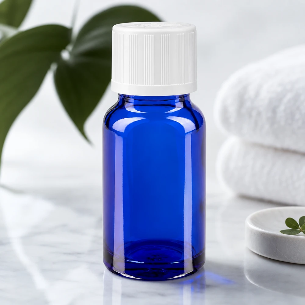 Flacon à usage pharmaceutique bleu 10ml bouchon compte-gouttes blanc séc. enf. 0.8mm Flacon en verre d'apothicaire bleu de 10 ml avec un bouchon de sécurité blanc pour enfants, posé sur du marbre à côté de serviettes pliées