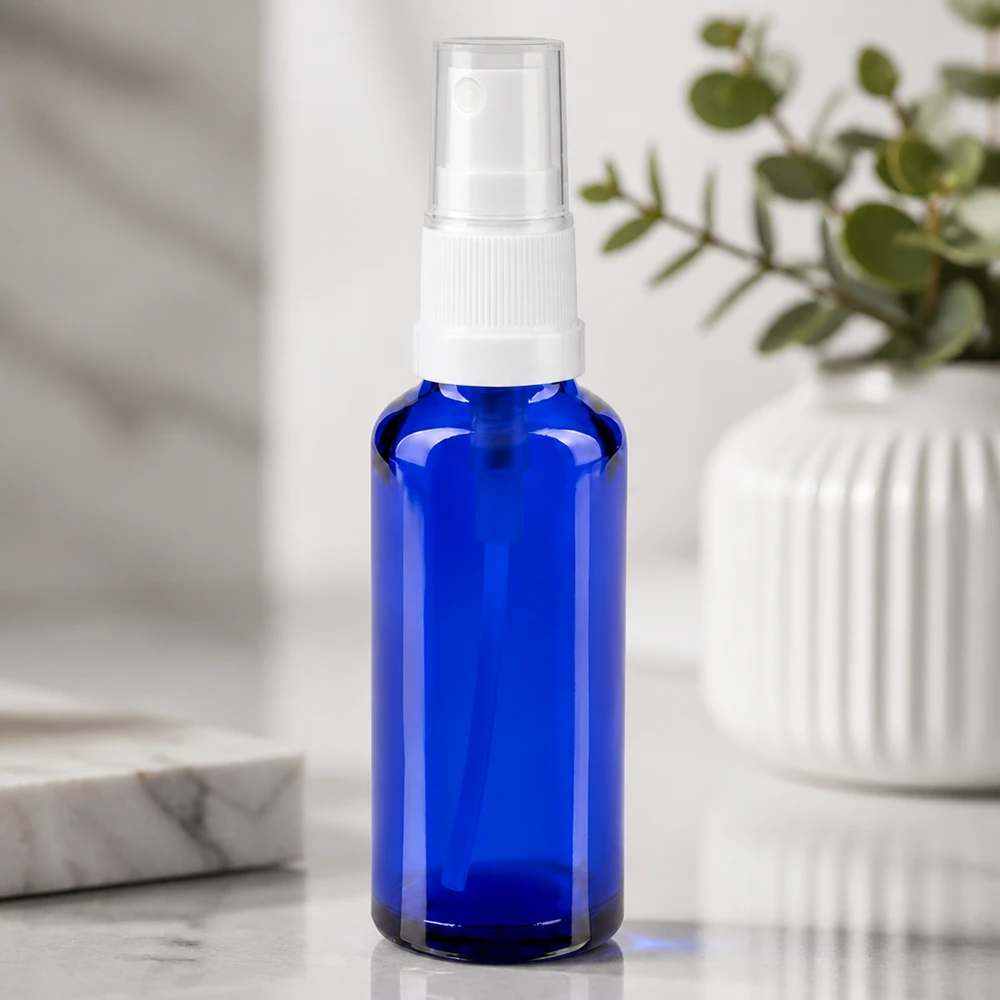 Flacon de pharmacie bleu 30ml embout spray blanc Flacon en verre de pharmacie bleu de 30 ml muni d'un vaporisateur blanc, posé sur un fond en marbre blanc